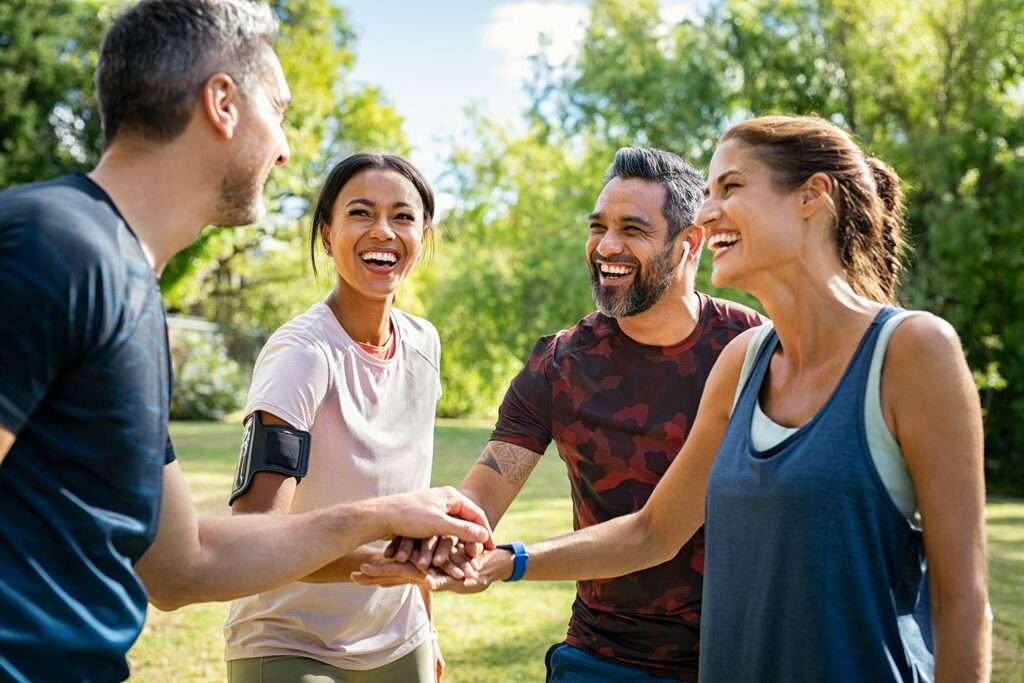 Collègues souriants qui joignent leurs mains en extérieur