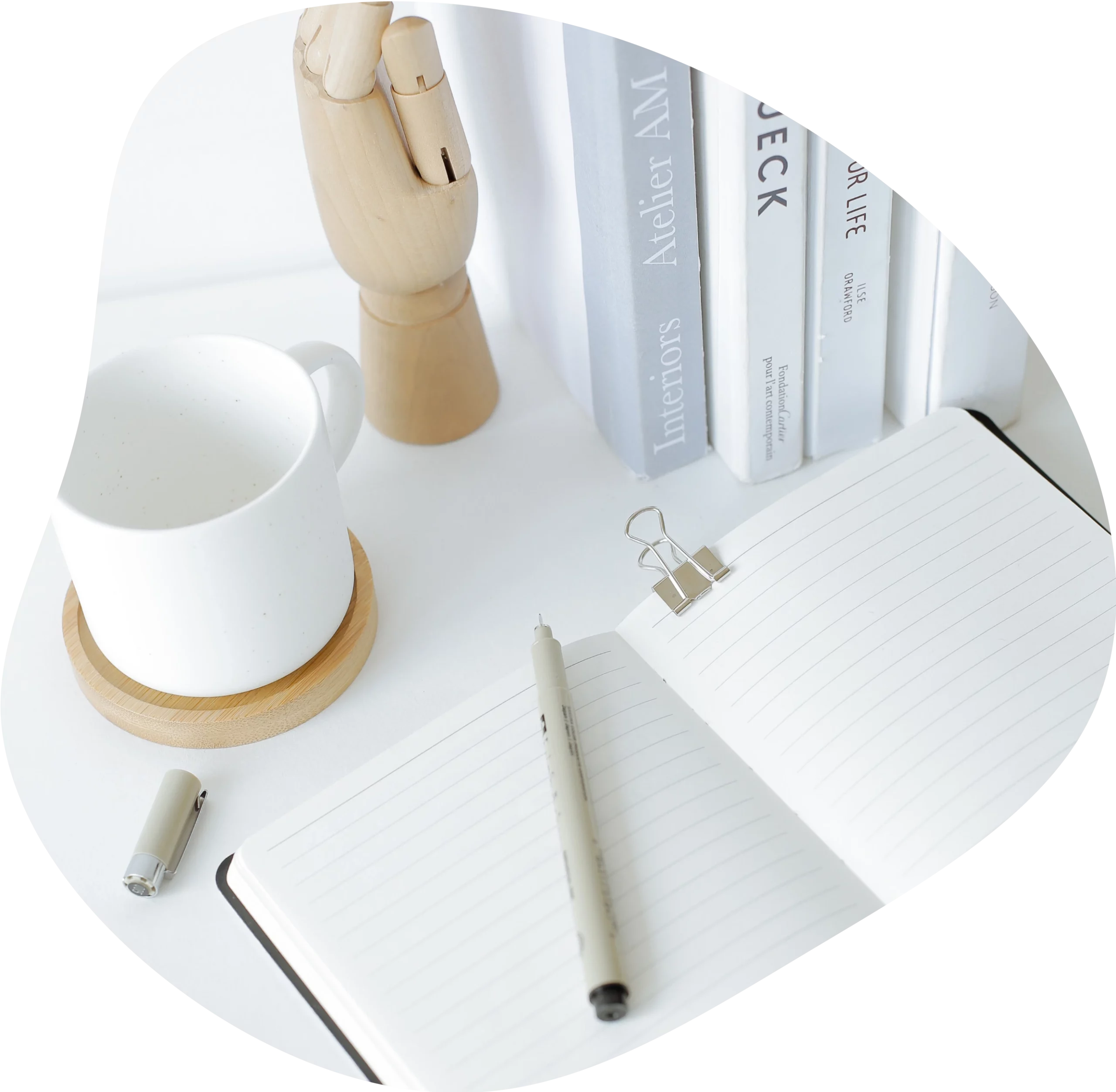 Vue de haut sur un carnet blanc, un stylo blanc, une tasse blanche et des livres