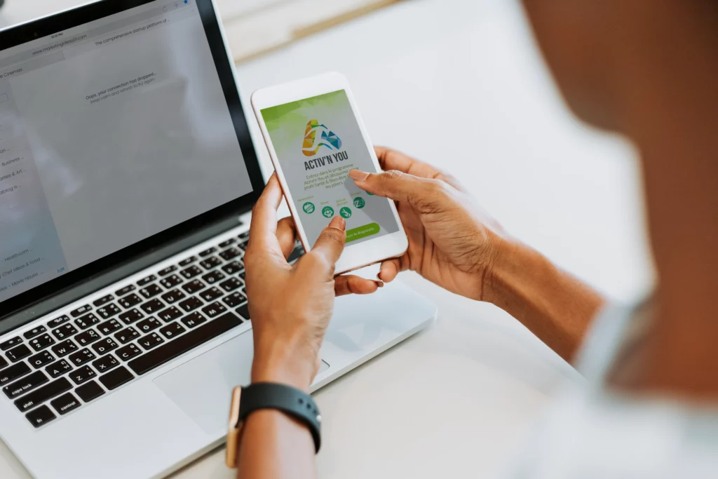 Application Activ’n You affichée sur un smartphone devant un ordinateur portable