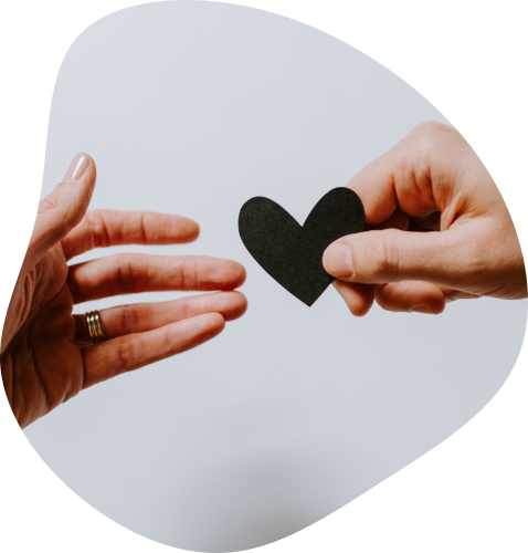 Gros plan sur une main qui donne un coeur en papier noir à une main d'une personne tierce.
