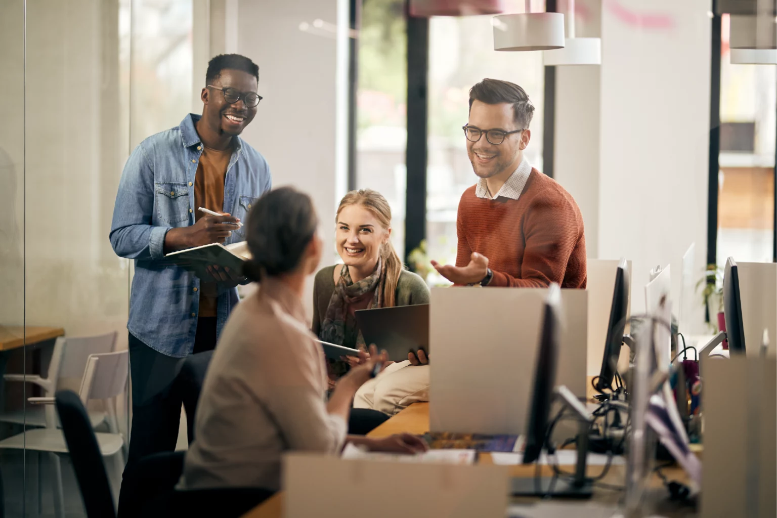 Équipe de salariés échangeant avec le sourire dans leur espace de travail